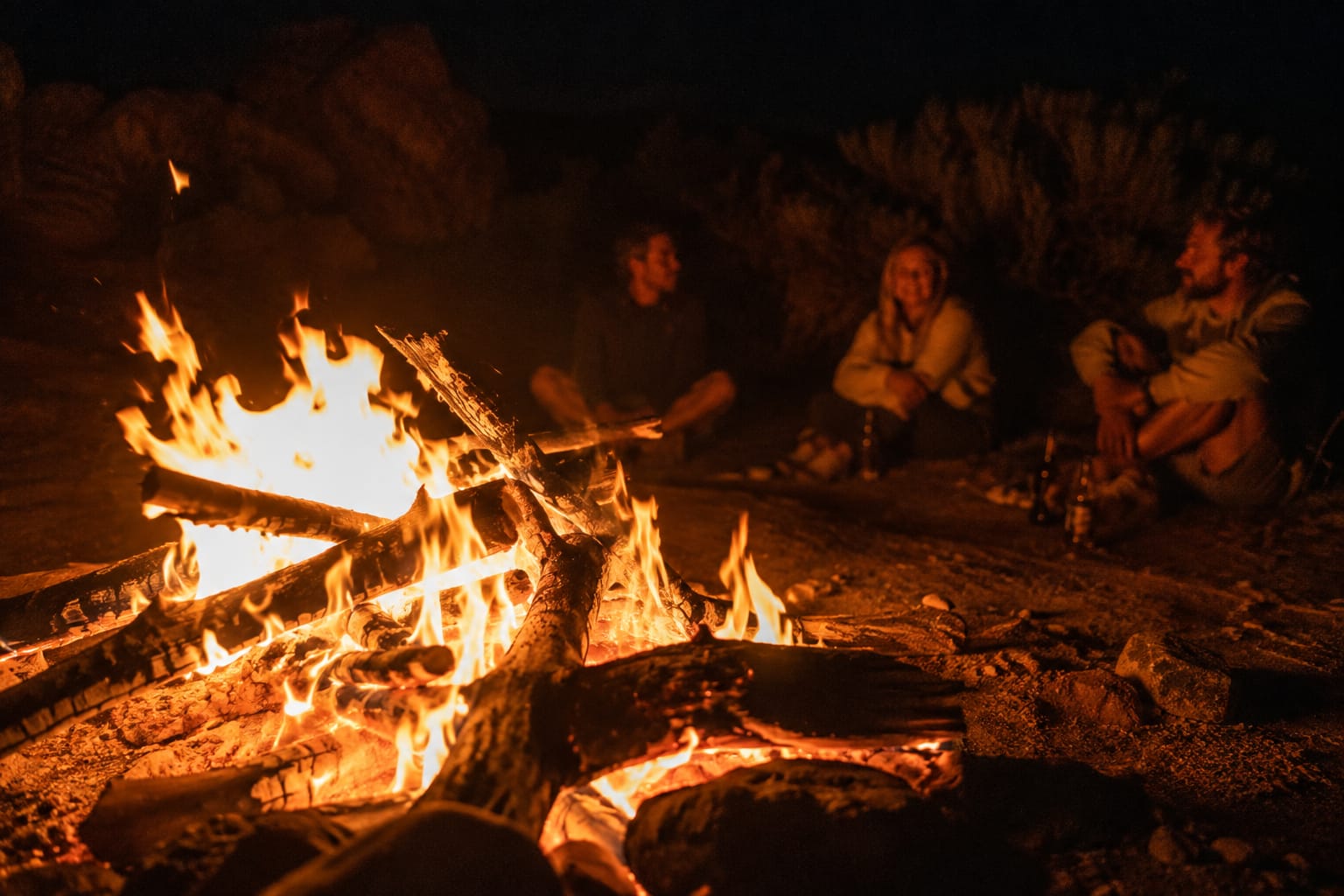 Gruppe sitzt abends gemeinsam am Lagerfeuer